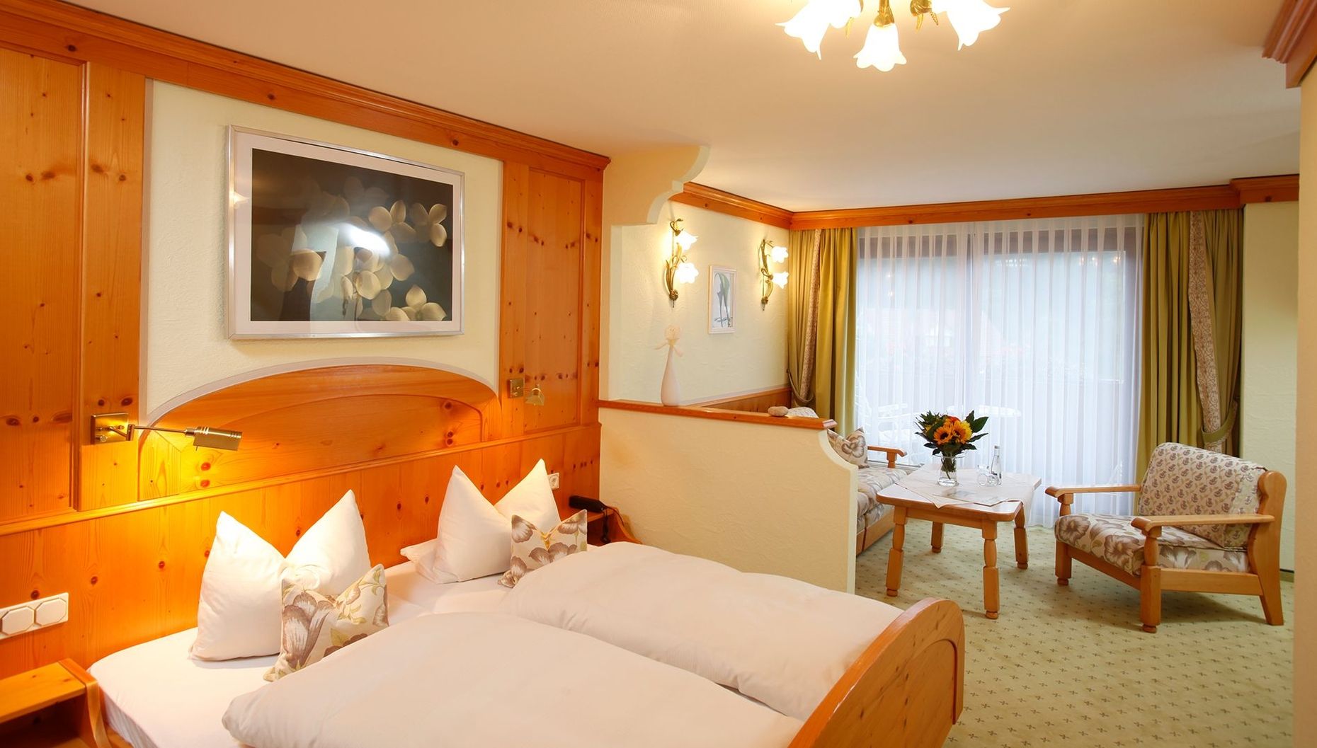 Chambre d'hôtel confortable avec boiseries chaleureuses, lit double avec oreillers blancs et petit coin salon.